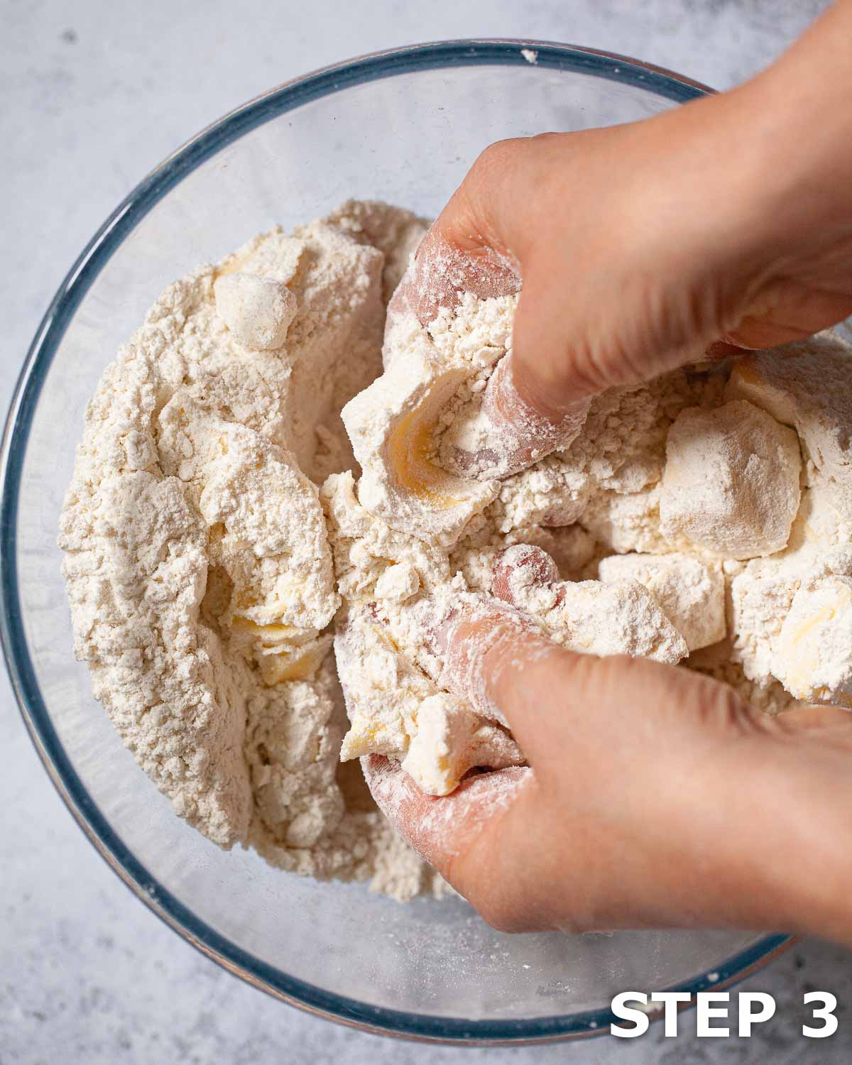 A person making shortcrust pastry by rubbing butter into flour in a bowl.