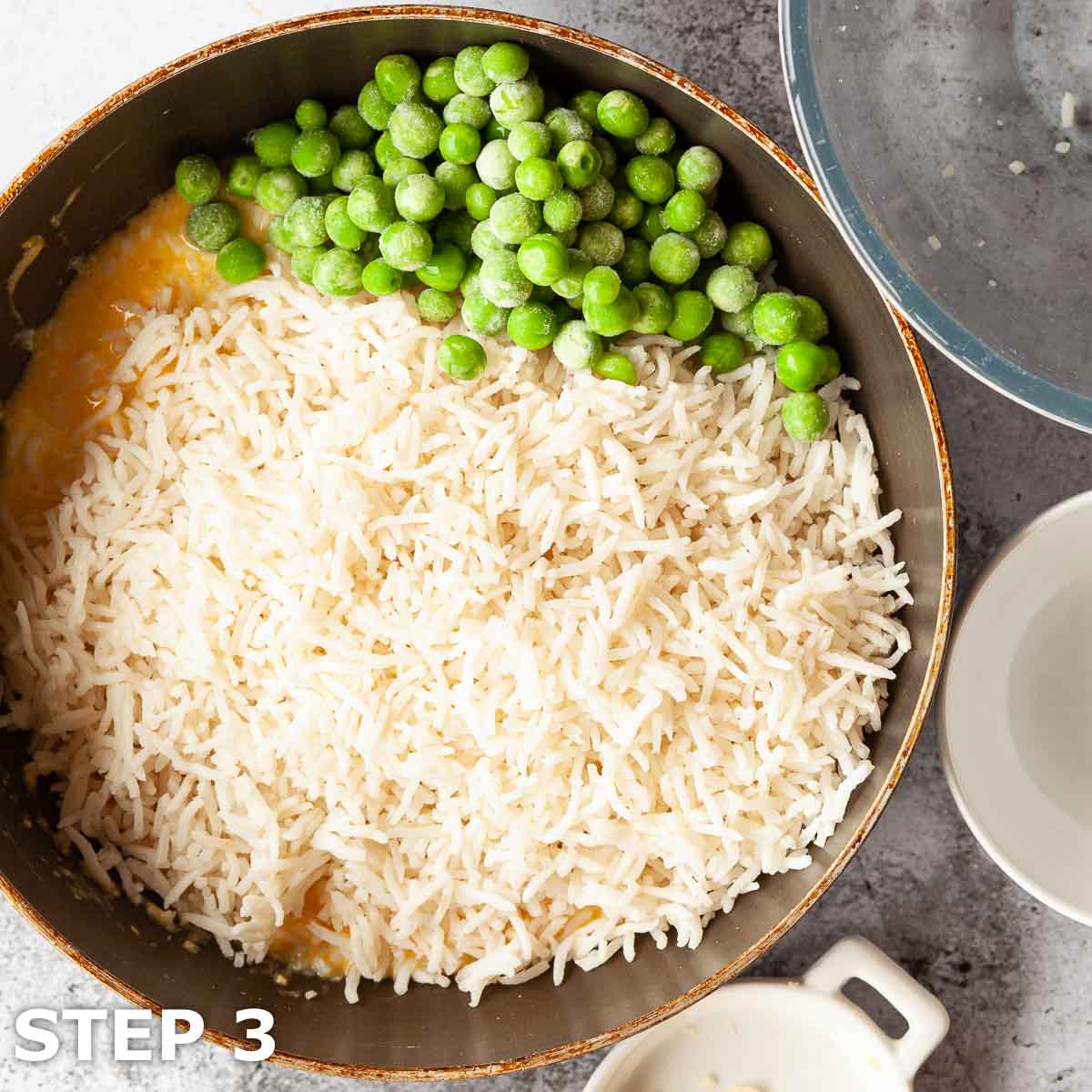 Rice and peas added to a pan of lightly cooked egg.