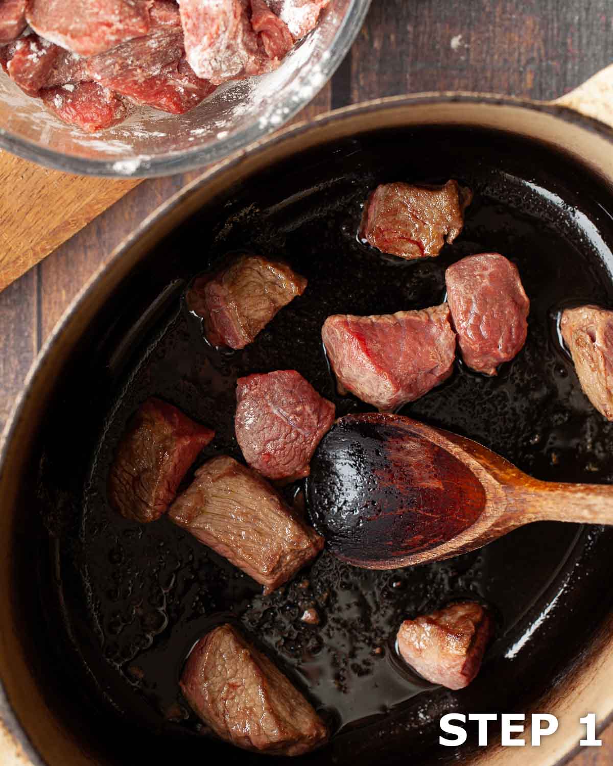 Stewing steak being browned in a dutch oven.
