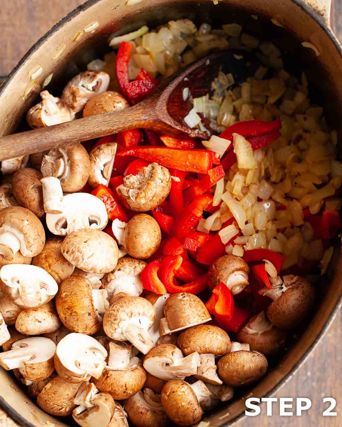 Mushrooms, red peppers and onions in a dutch oven.
