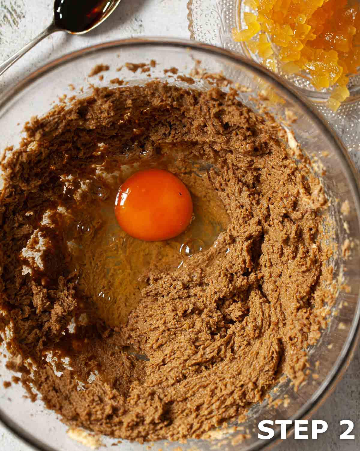 An egg in a bowl of cake batter ahead of being mixed in.