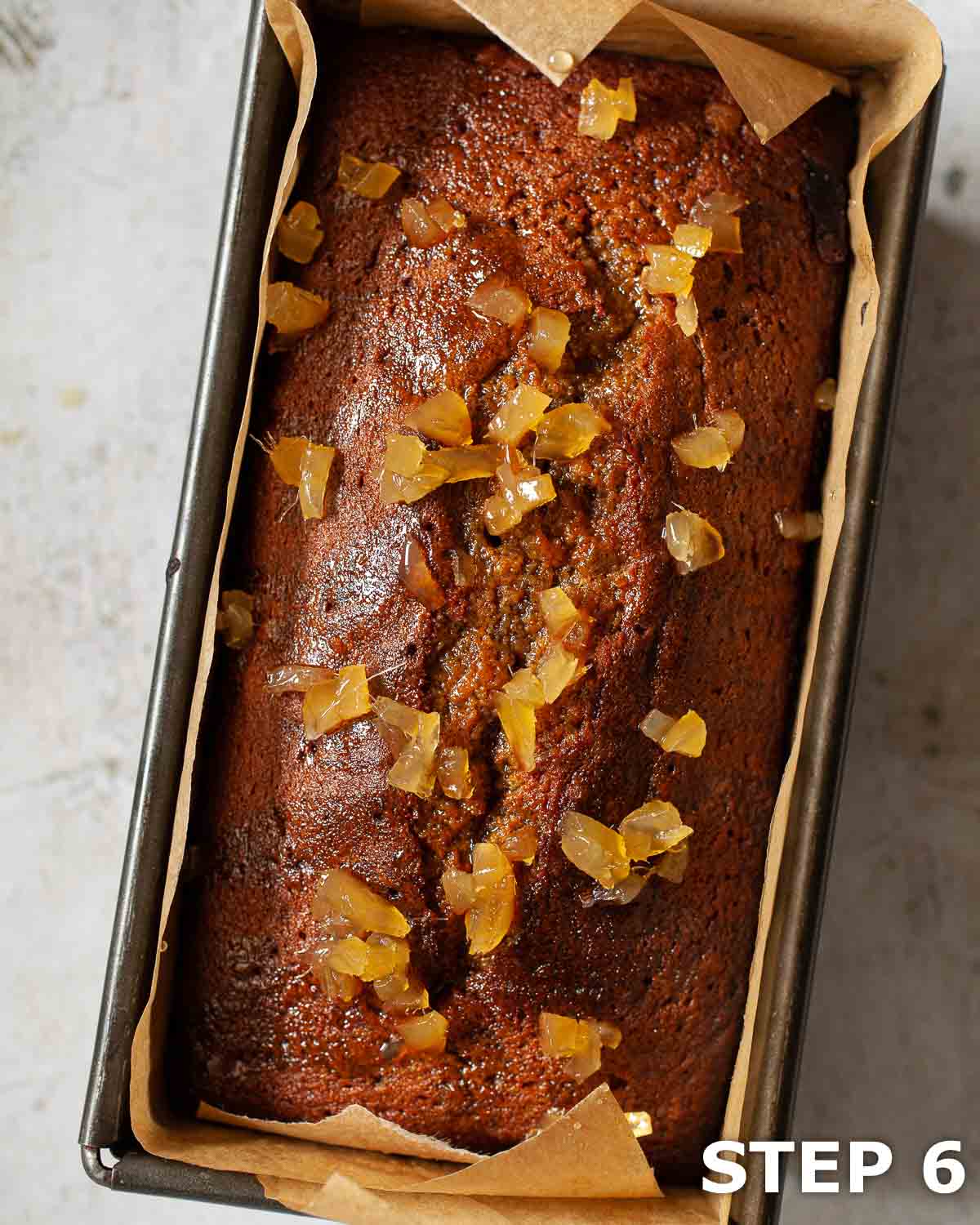 Ginger loaf cake topped with stem ginger in a baking tin.