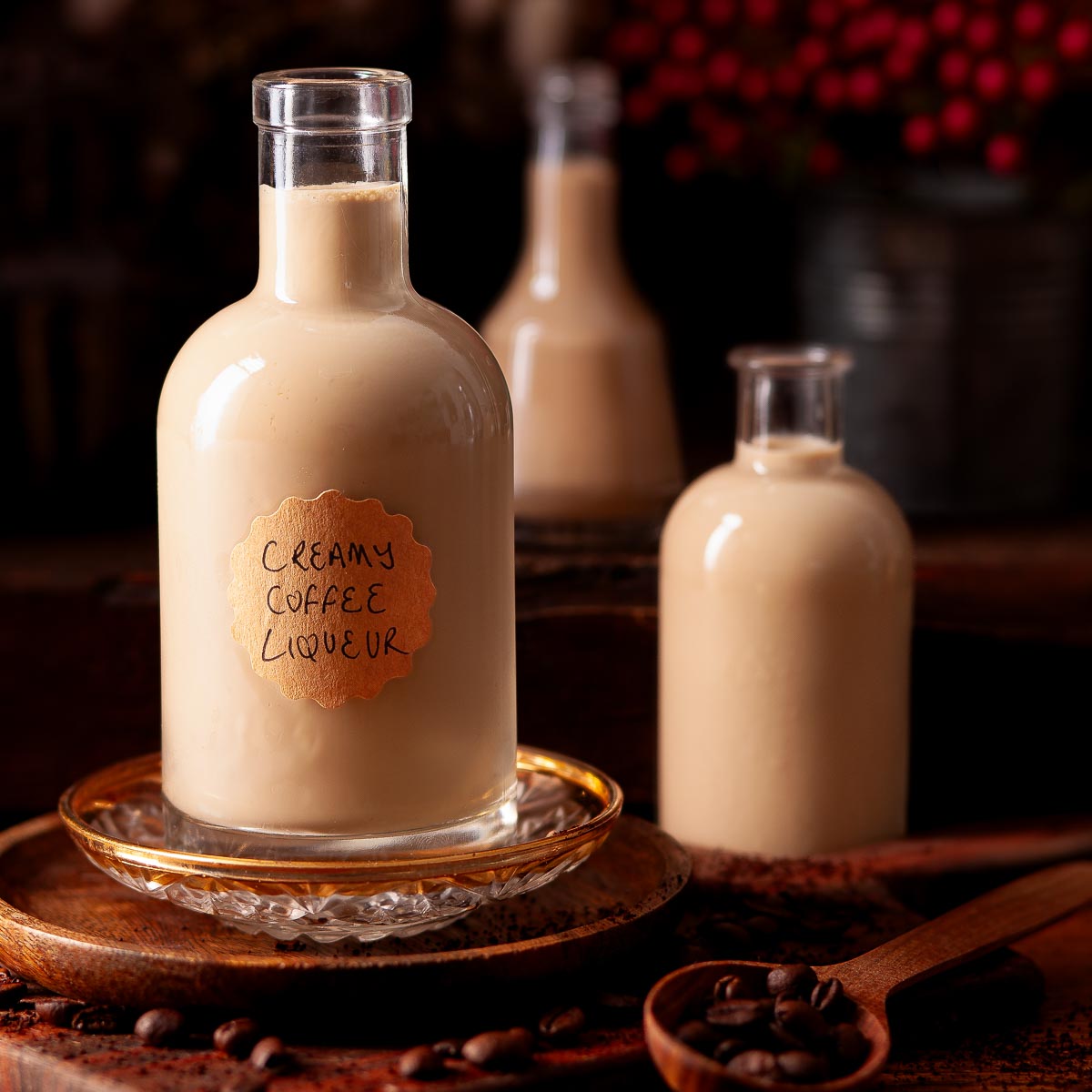 Three bottles of homemade coffee liqueur surrounded by coffee beans.