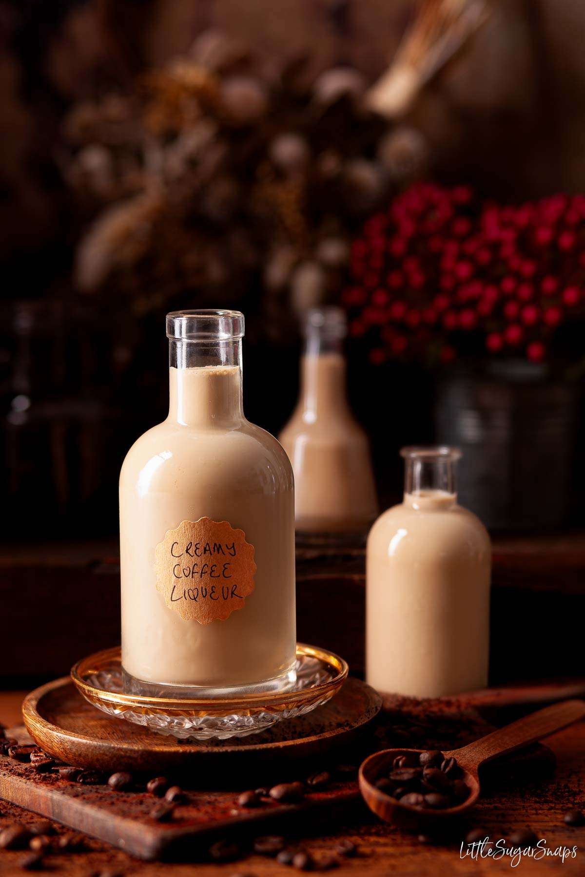 Three bottles of homemade coffee cream liqueur surrounded by coffee beans.