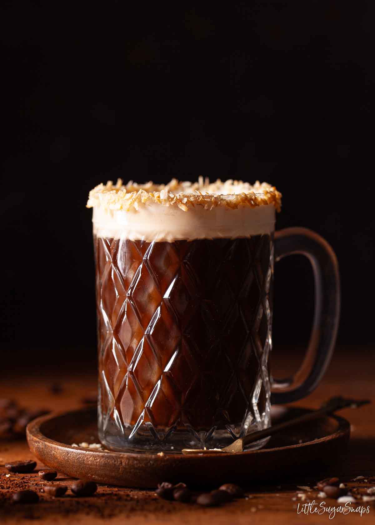 Coffee and coconut drink with cream float in a glass rimmed with toasted coconut.