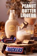 Labelled peanut butter liqueur served over ice with slices of Snickers chocolate on a cocktail pick.