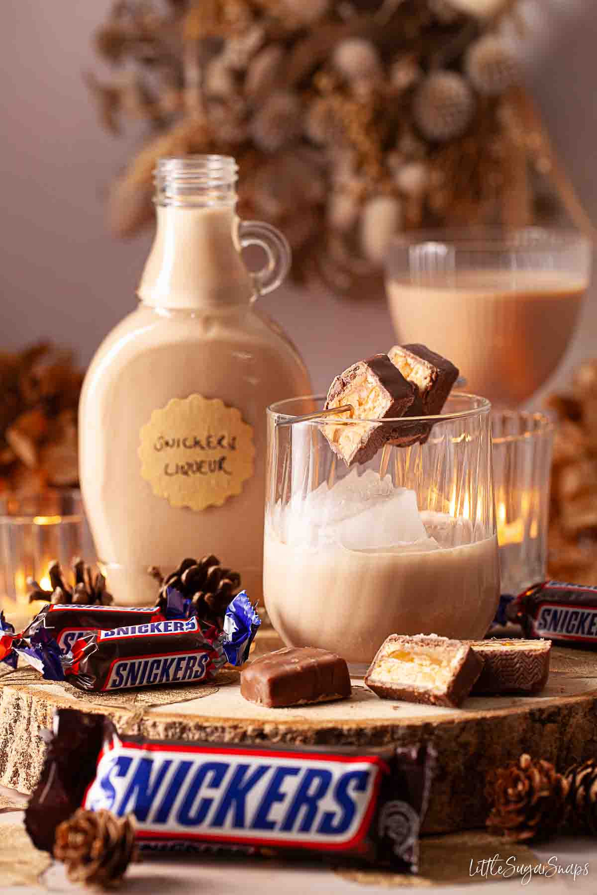 Peanut butter liqueur served over ice with slices of Snickers chocolate on a cocktail pick.