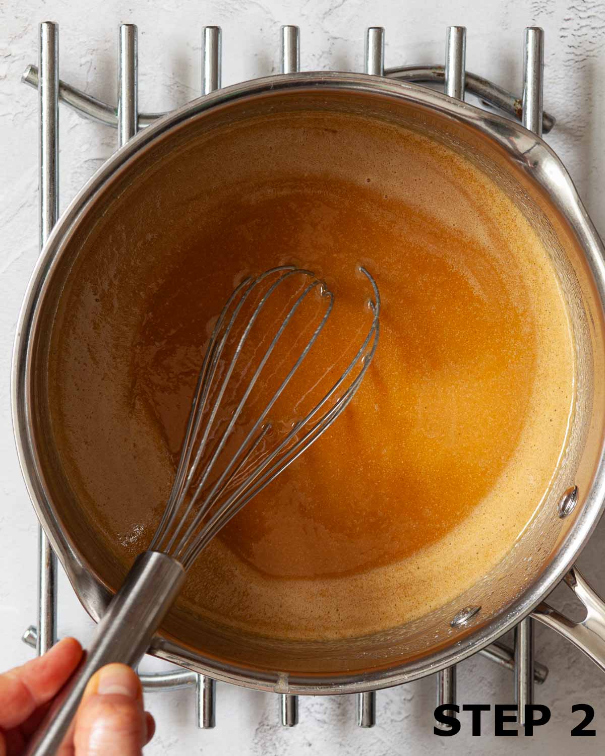 A person whisking melted ingredients for peanut butter flapjack in a pan.