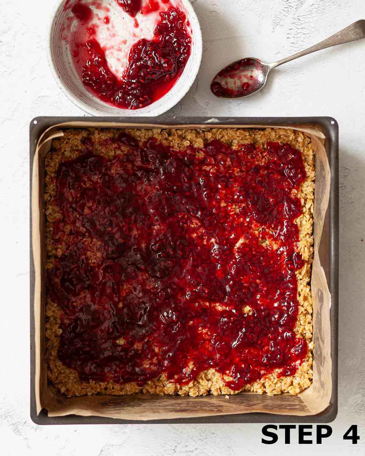 A layer of jam spread over mixture for flapjack with peanut butter.