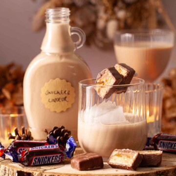 Peanut butter liqueur served over ice with slices of Snickers chocolate on a cocktail pick.