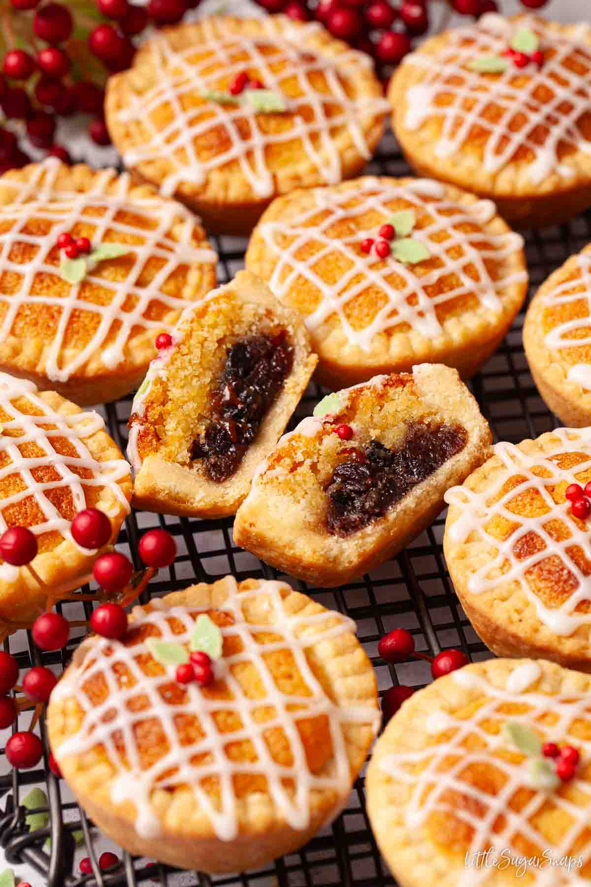A cut open frangipane mince pie surrounded by whole pies on a wire rack.