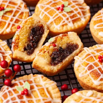 A cut open frangipane mince pie surrounded by whole pies on a wire rack.