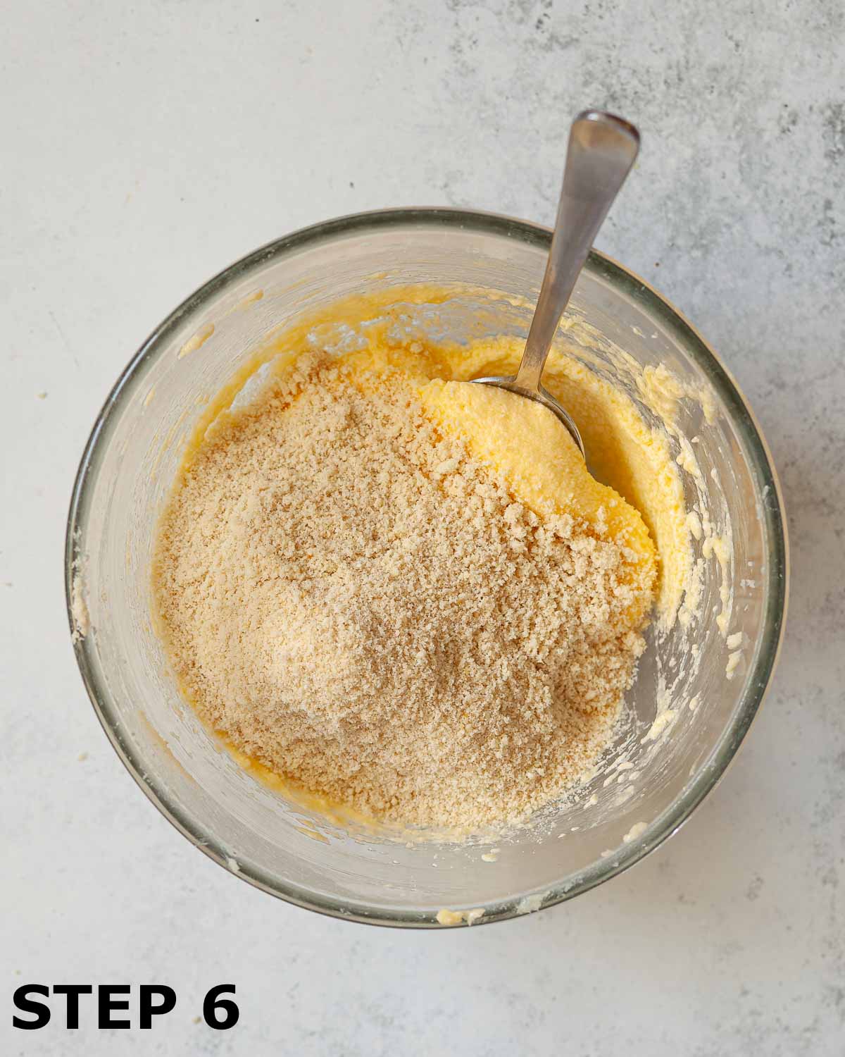 Ground almonds about to be mixed into frangipane batter with a metal spoon.