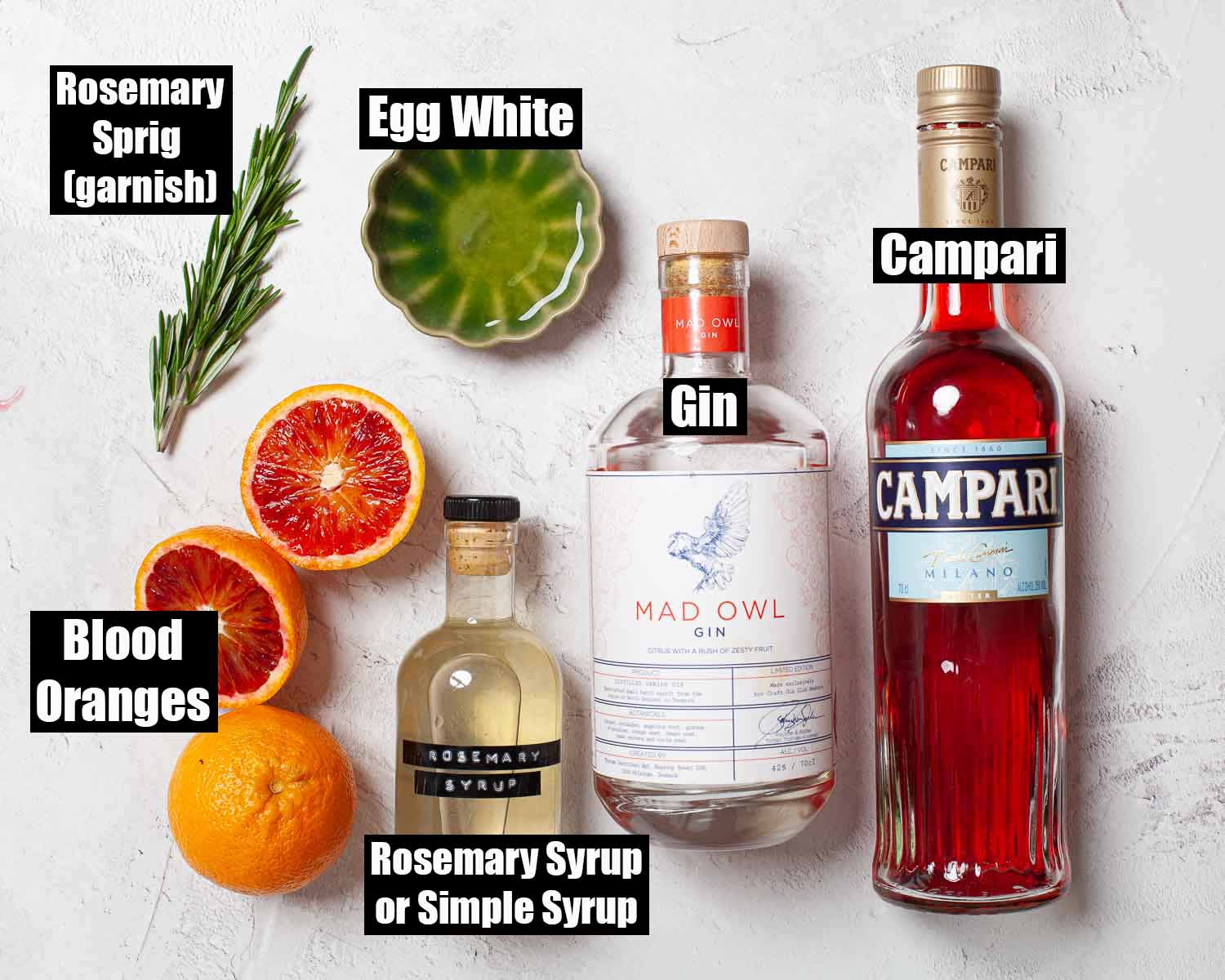 Labelled ingredients for a blood orange drink with gin and rosemary syrup.