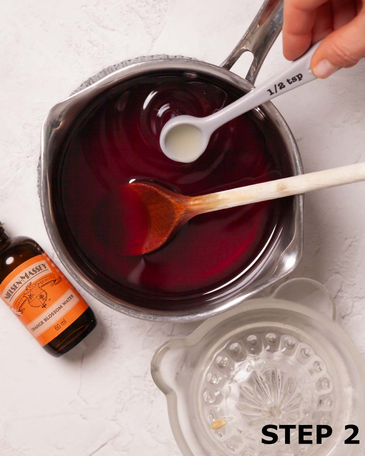 Lemon juice being added to pomegranate syrup in saucepan.