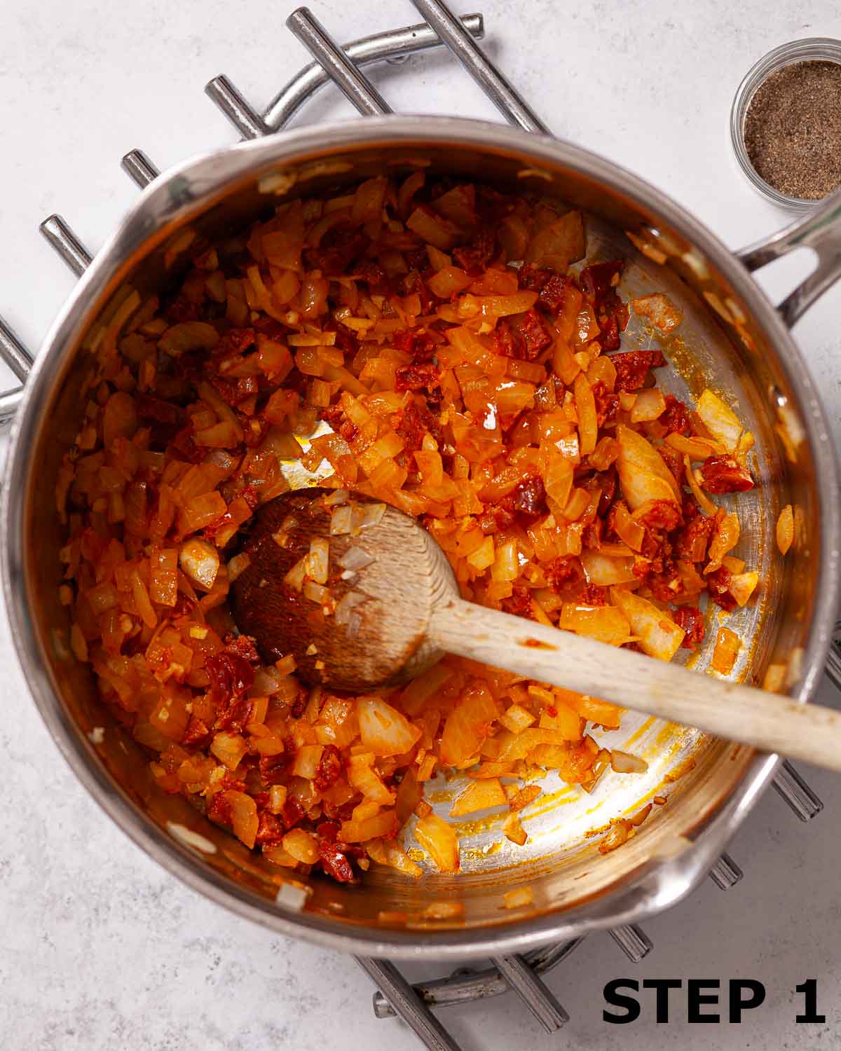 Softened onion and chorizo in a large saucepan with a wooden spoon.