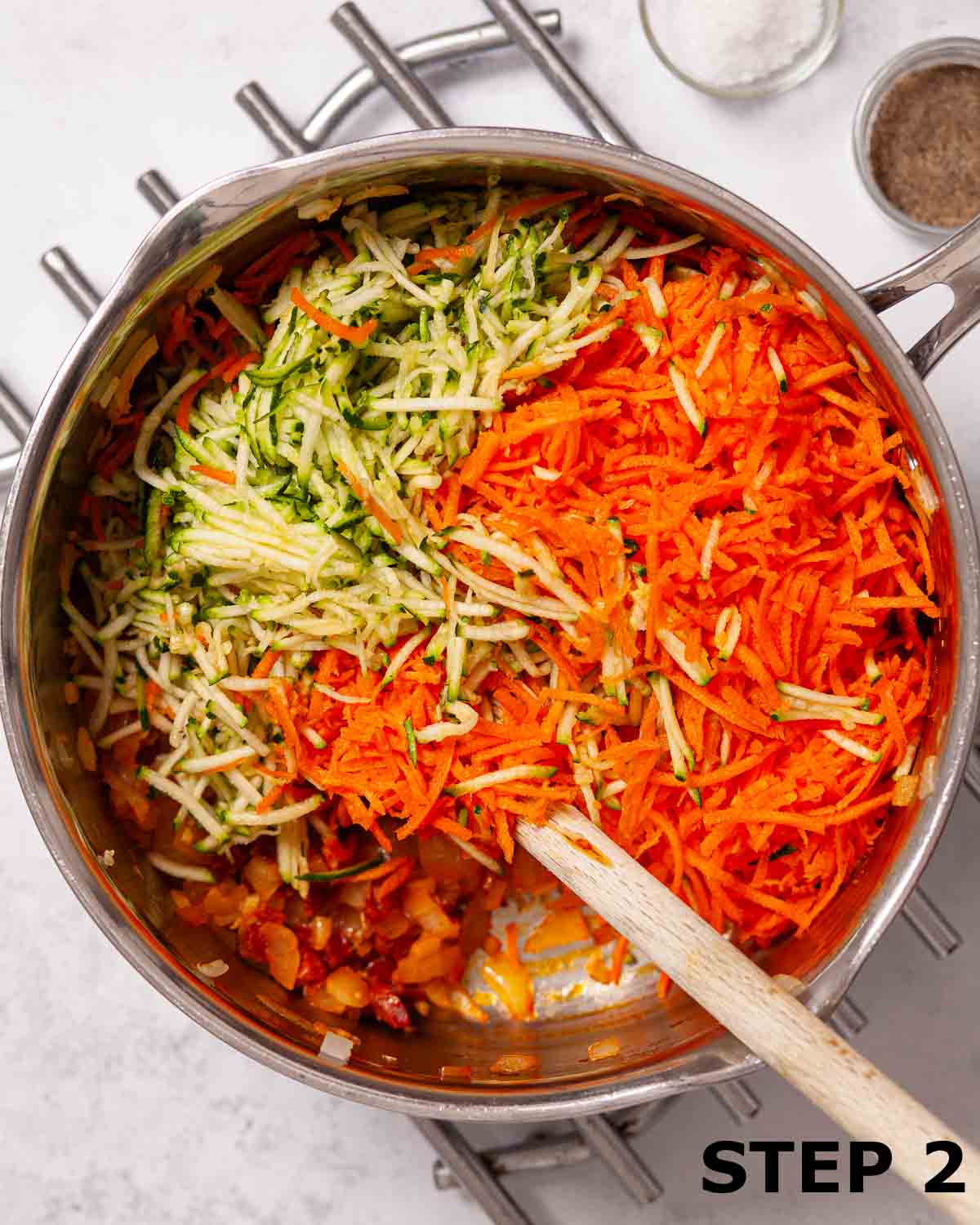 Grated carrot and courgette in a saucepan with cooked onion and chorizo.