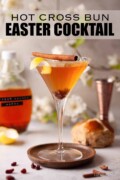 Labelled Easter cocktail in a martini glass with a bottle of hot cross bun vodka alongside.