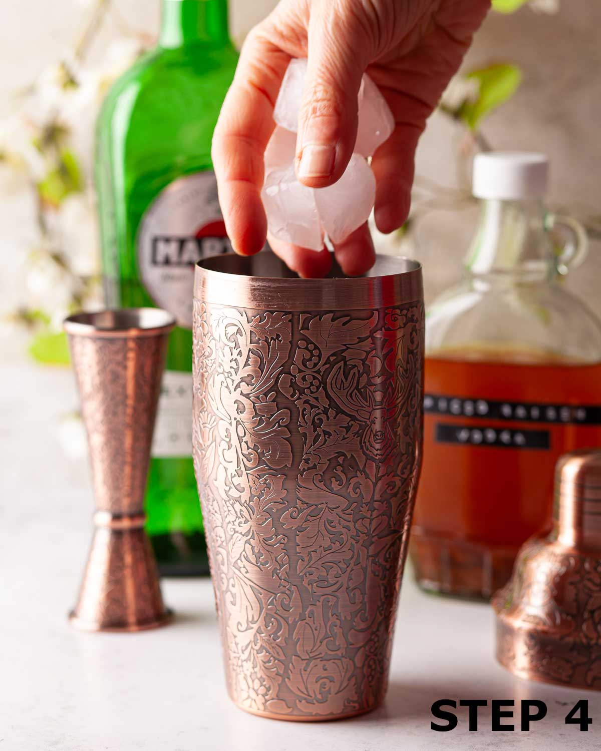 A person putting ice cubes into a cocktail shaker.