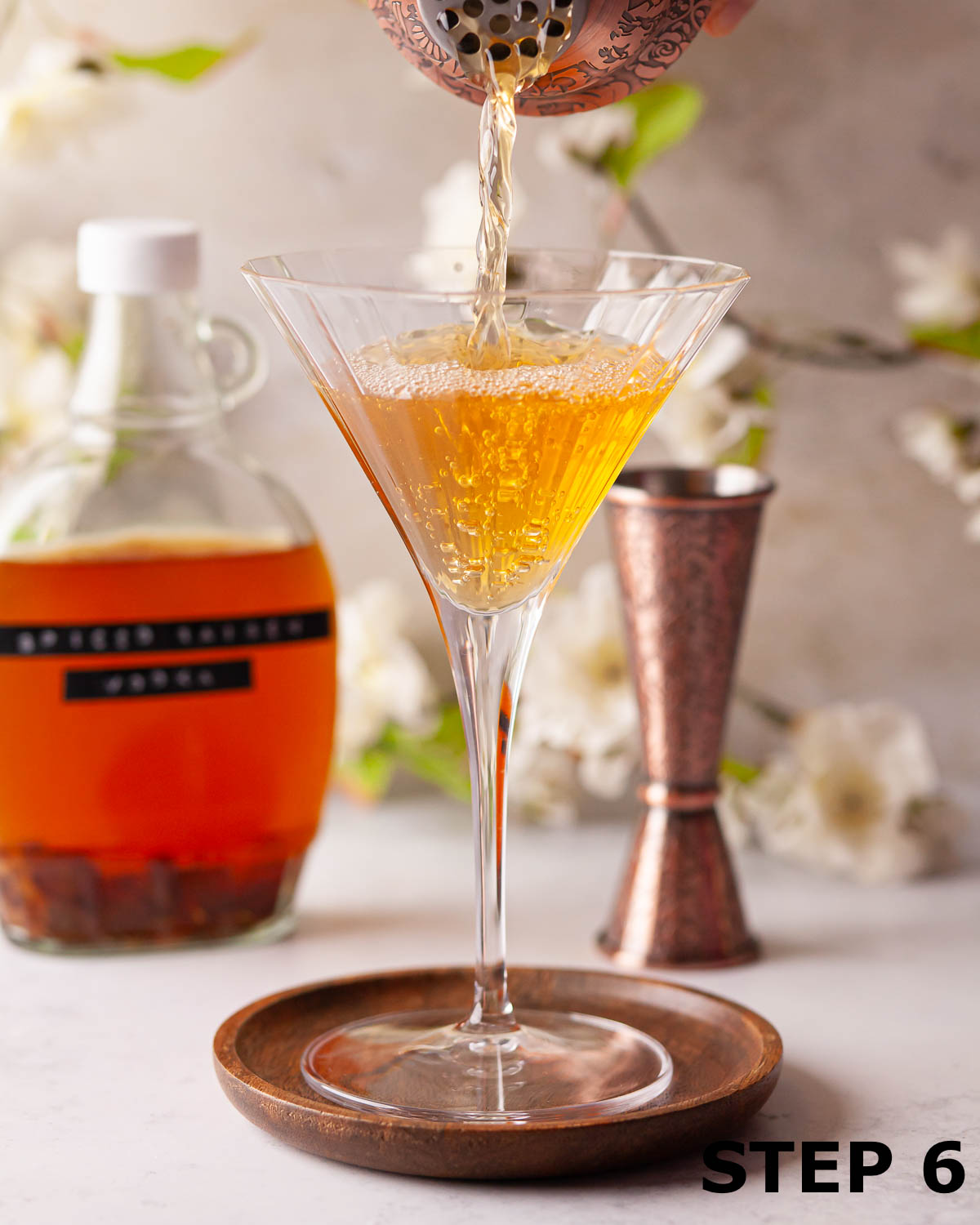 A person pouring an Easter cocktail made with hot cross bun vodka into a serving glass.