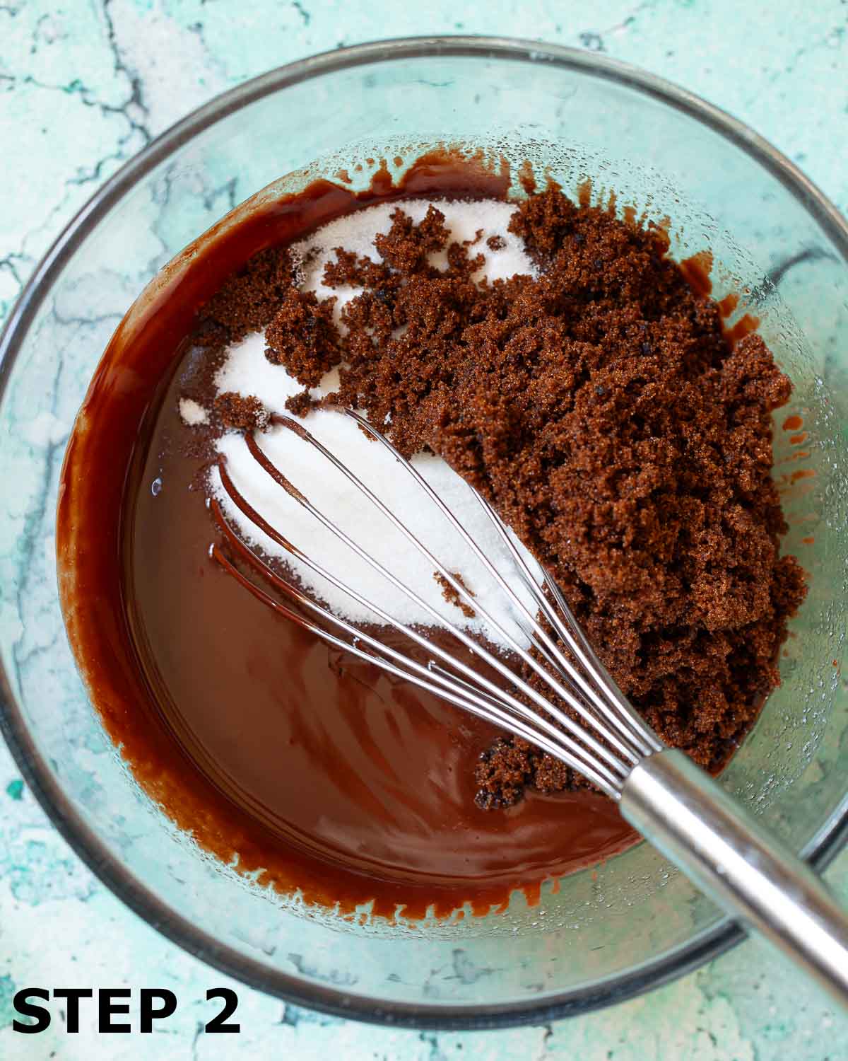 Dark and white sugar about to be mixed into melted chocolayte and butter with a balloon whisk.