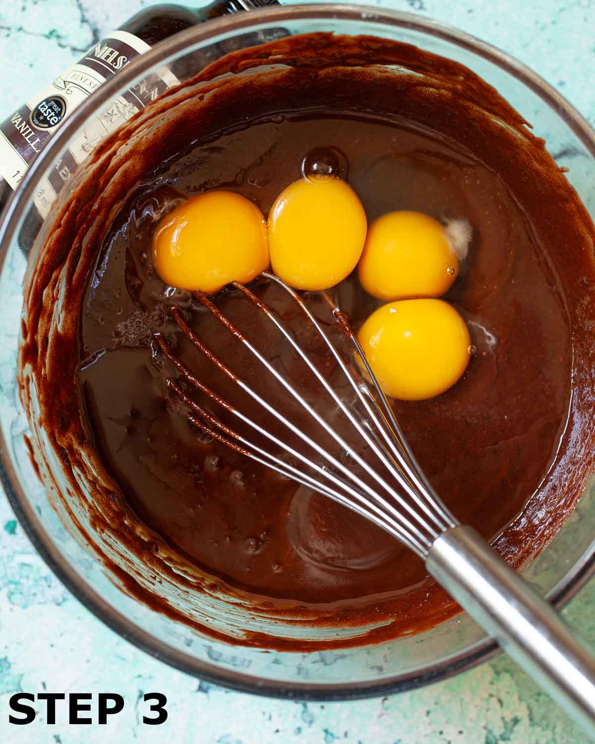Four eggs ready to be mixed into brownie batter with a balloon whisk.