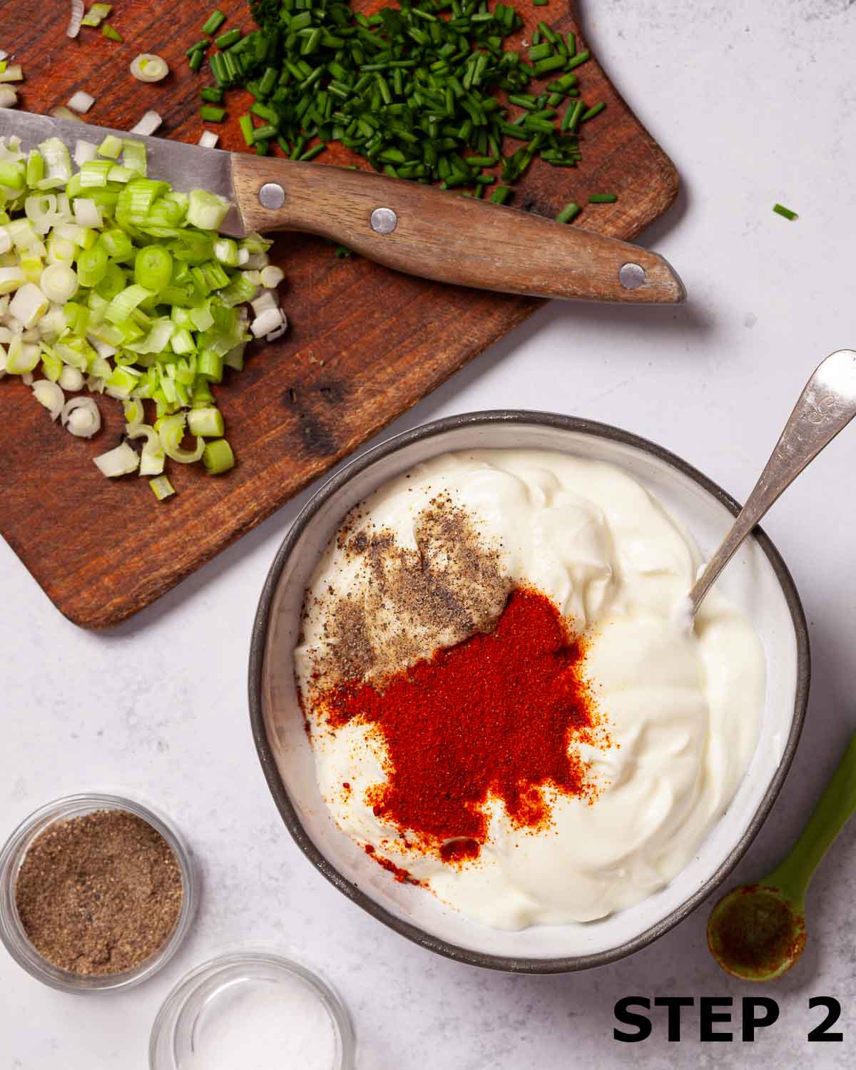 Paprika, salt and pepper scattered over soured cream dip in a bowl.