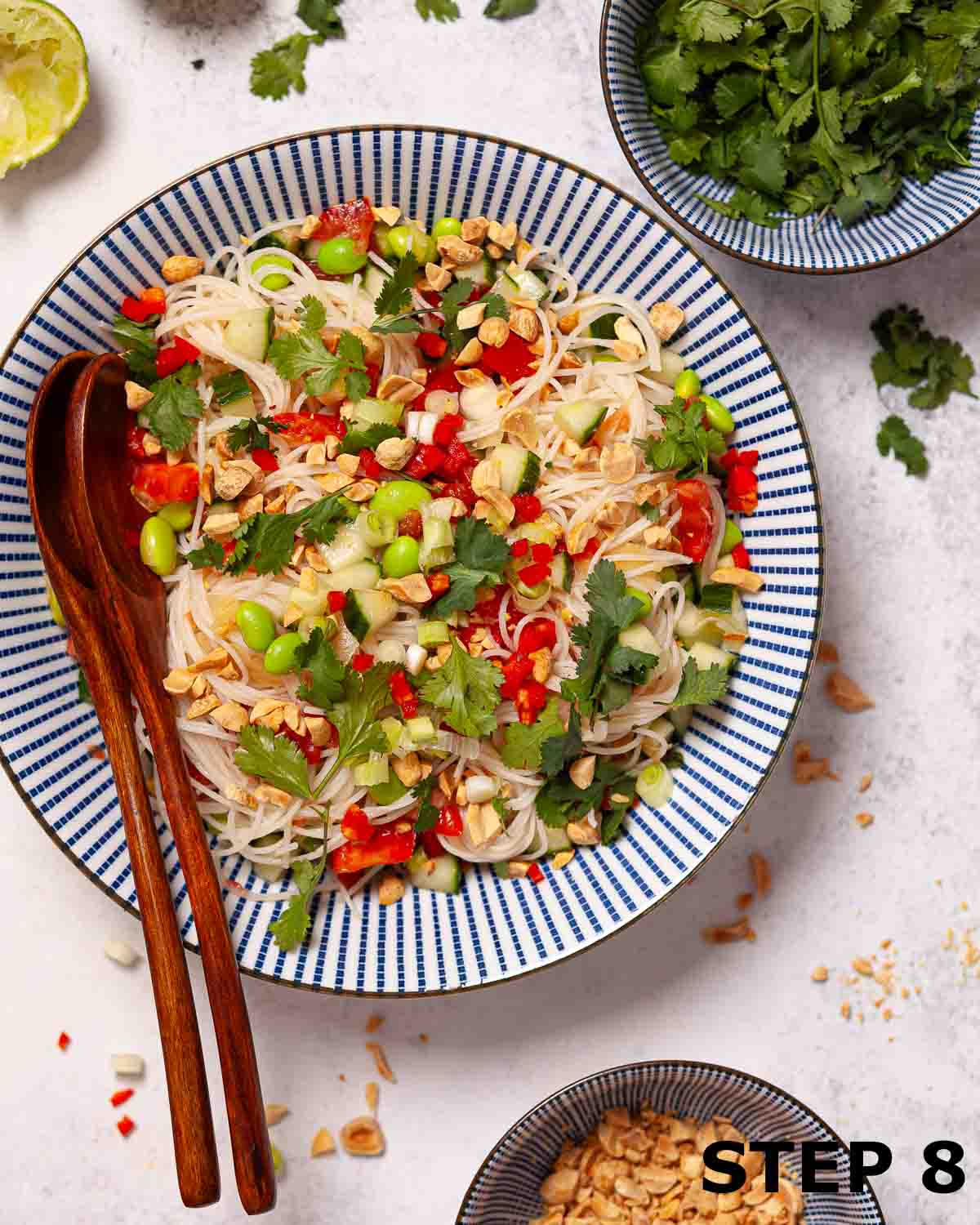 A bowl of cucumber noodle salad with peanut, chilli and coriander sprinkled on top.