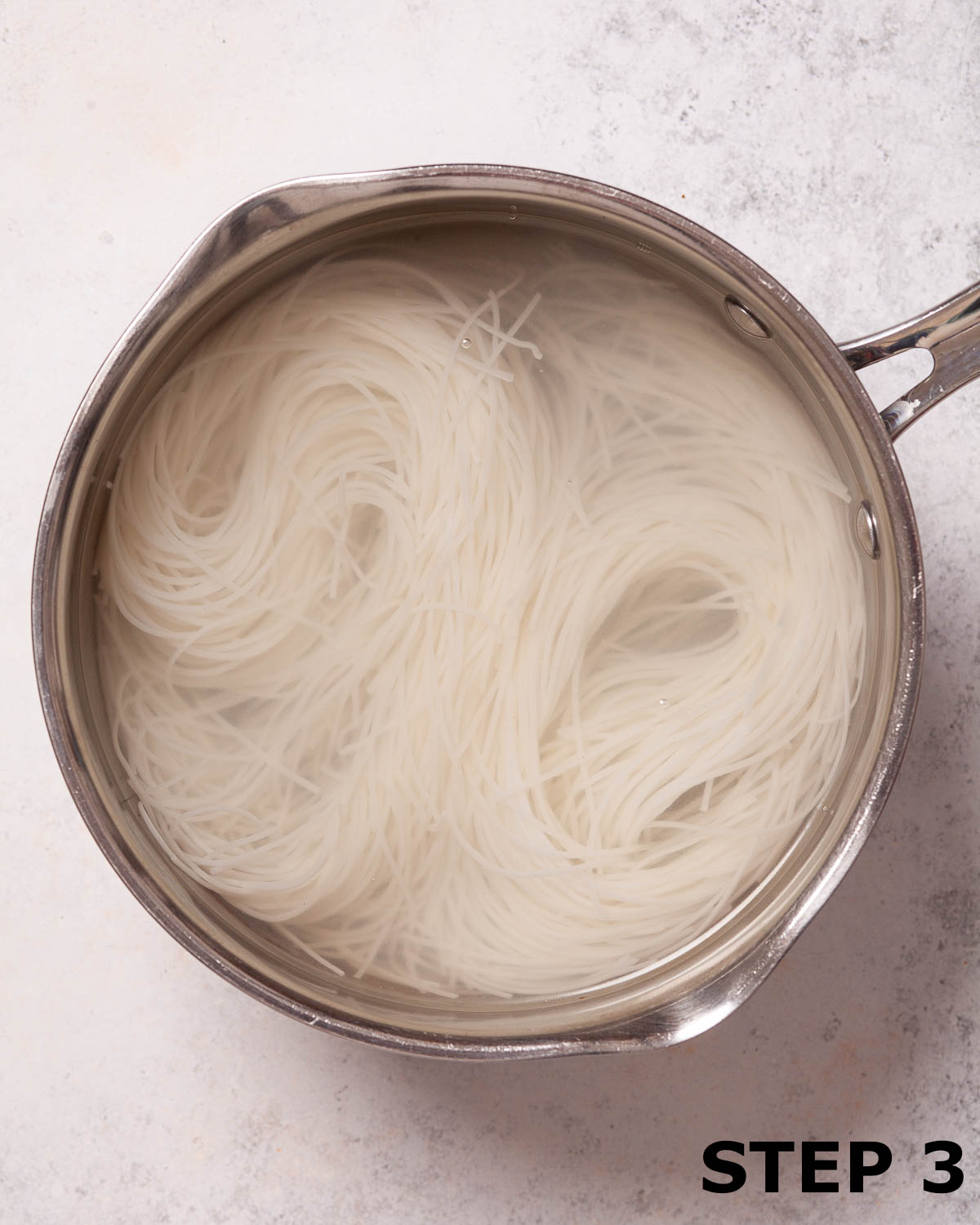 Vermicilli rice noodles soaking in a pan of water.