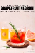 Labelled grapefruit and gin cocktail garnished with grapefruit twist and fresh rosemary.