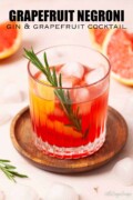 A grapefruit negroni cocktail garnished with grapefruit twist and fresh rosemary.