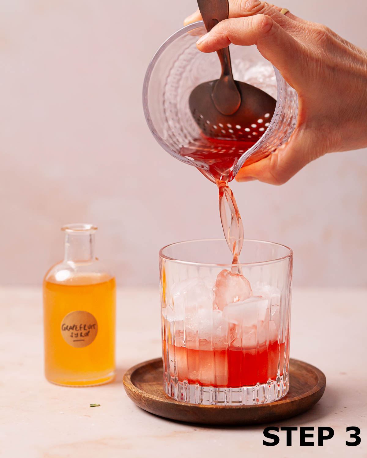 A grapefruit and gin cocktail being pouring into a tumbler.