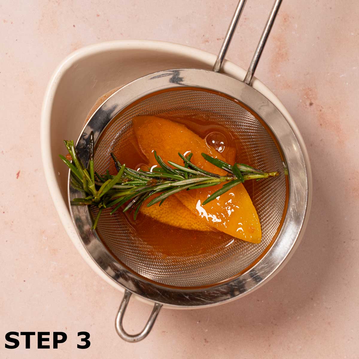 Grapefruit zest and a rosemary sprig in a sieve.