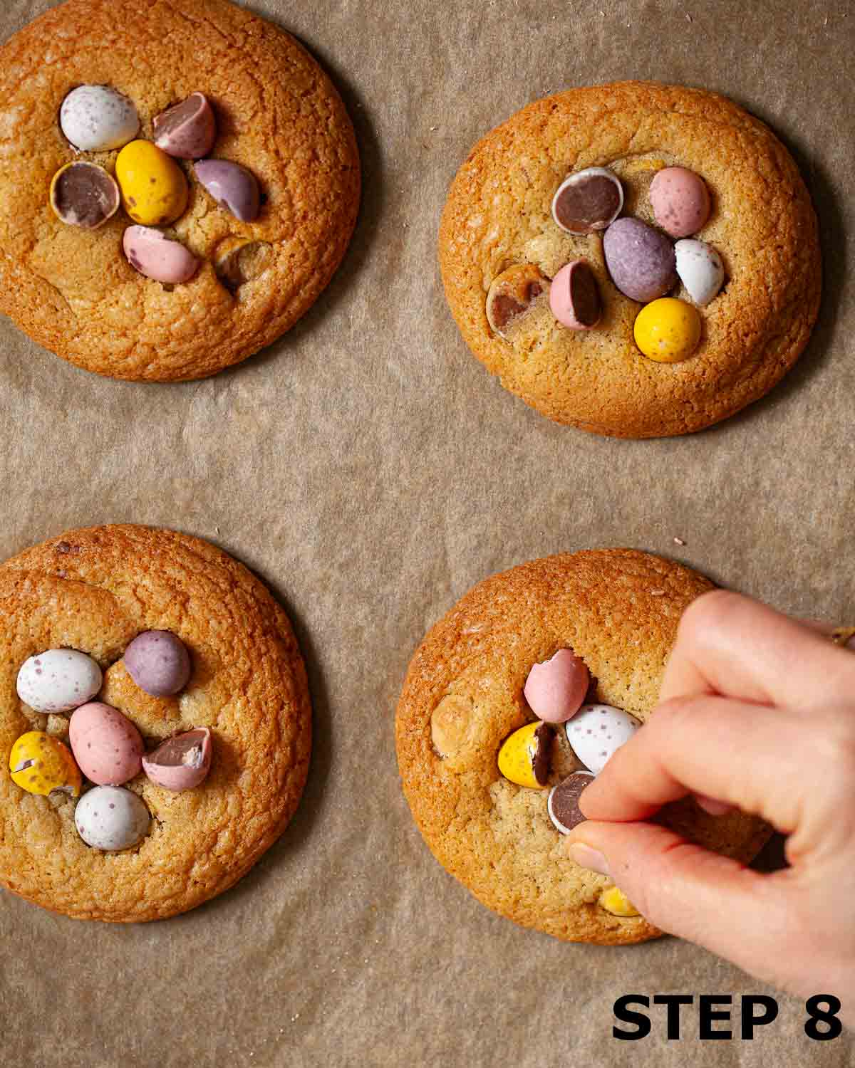A person decorating warm cookies with pieces of Cadbury Mini Eggs.