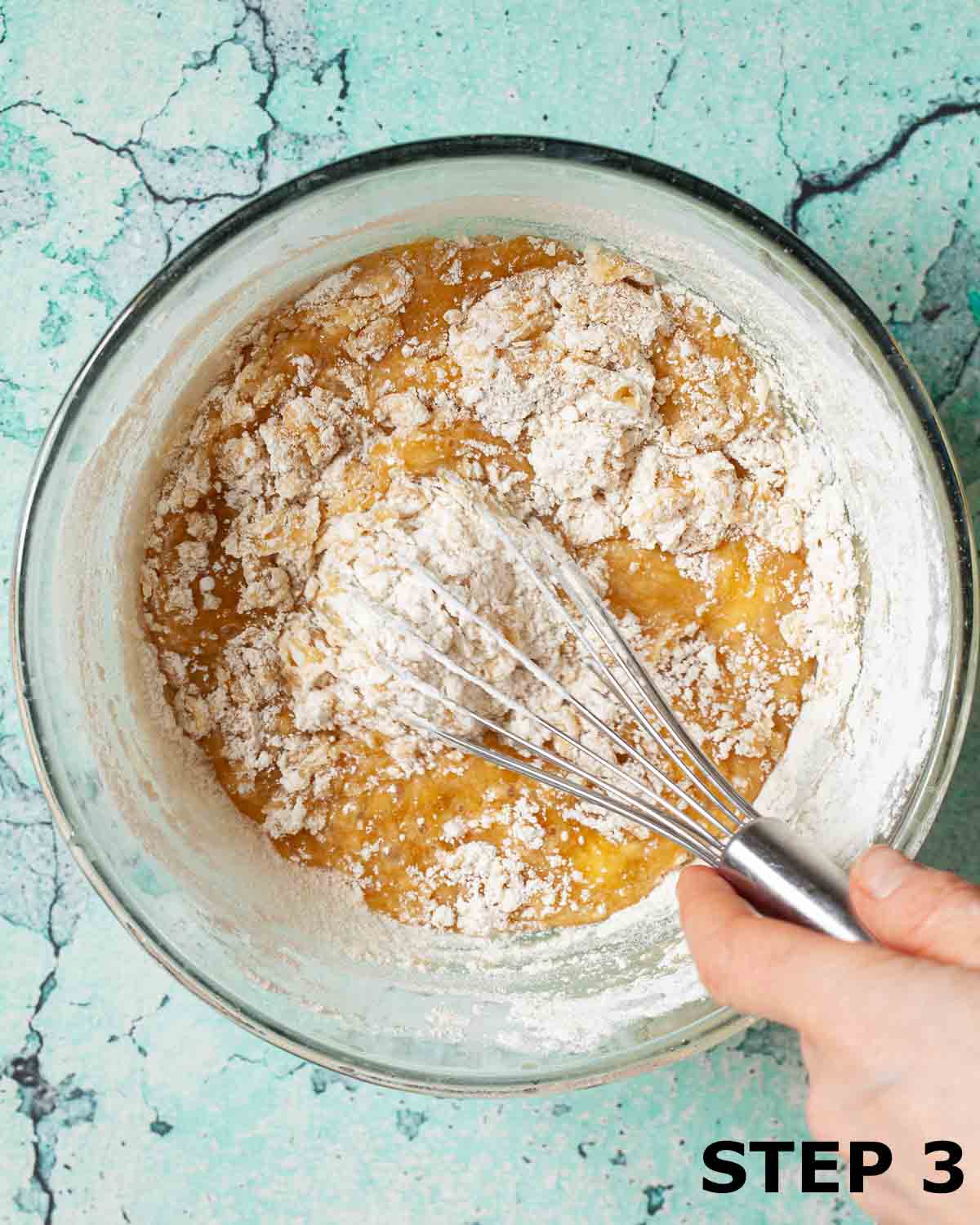 A person mixing flour into other ingredients to make cookie dough.