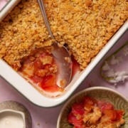 Apple & rhubarb crumble with ginger being served from a large baking dish into bowls.