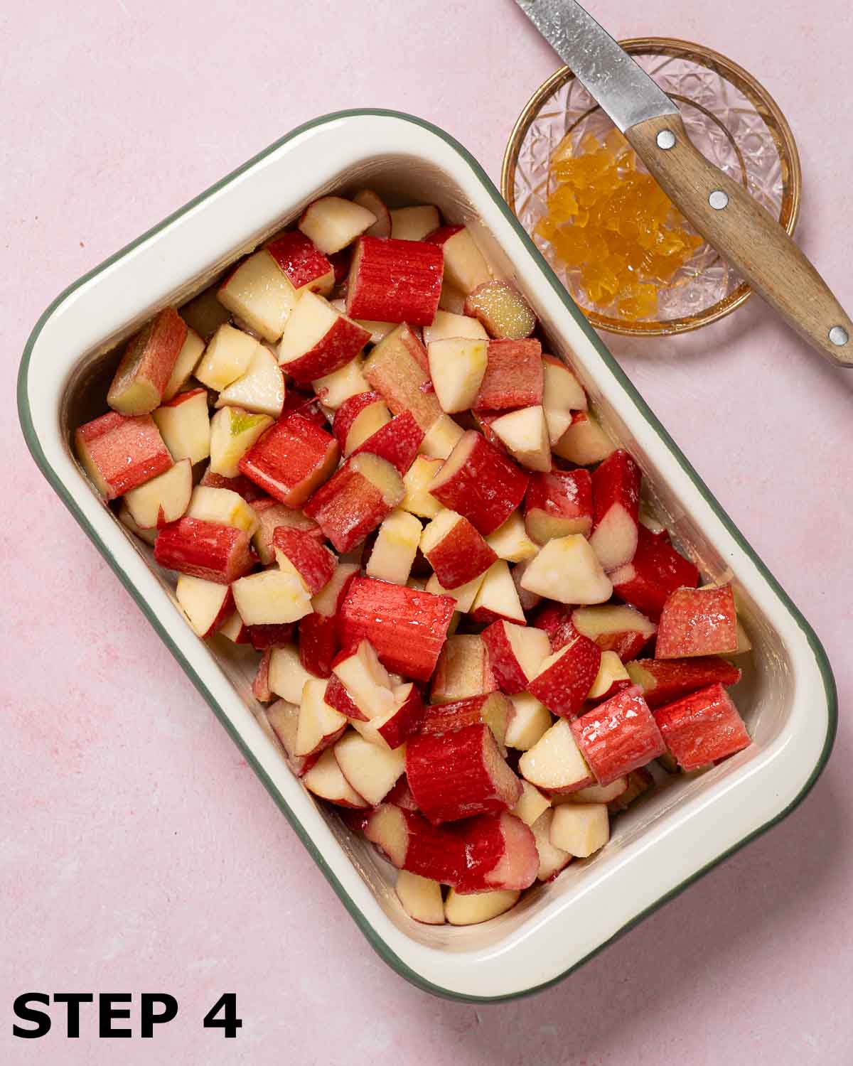 A baking dish filled with apple and rhubarb pieces with chopped stem ginger on a plate.