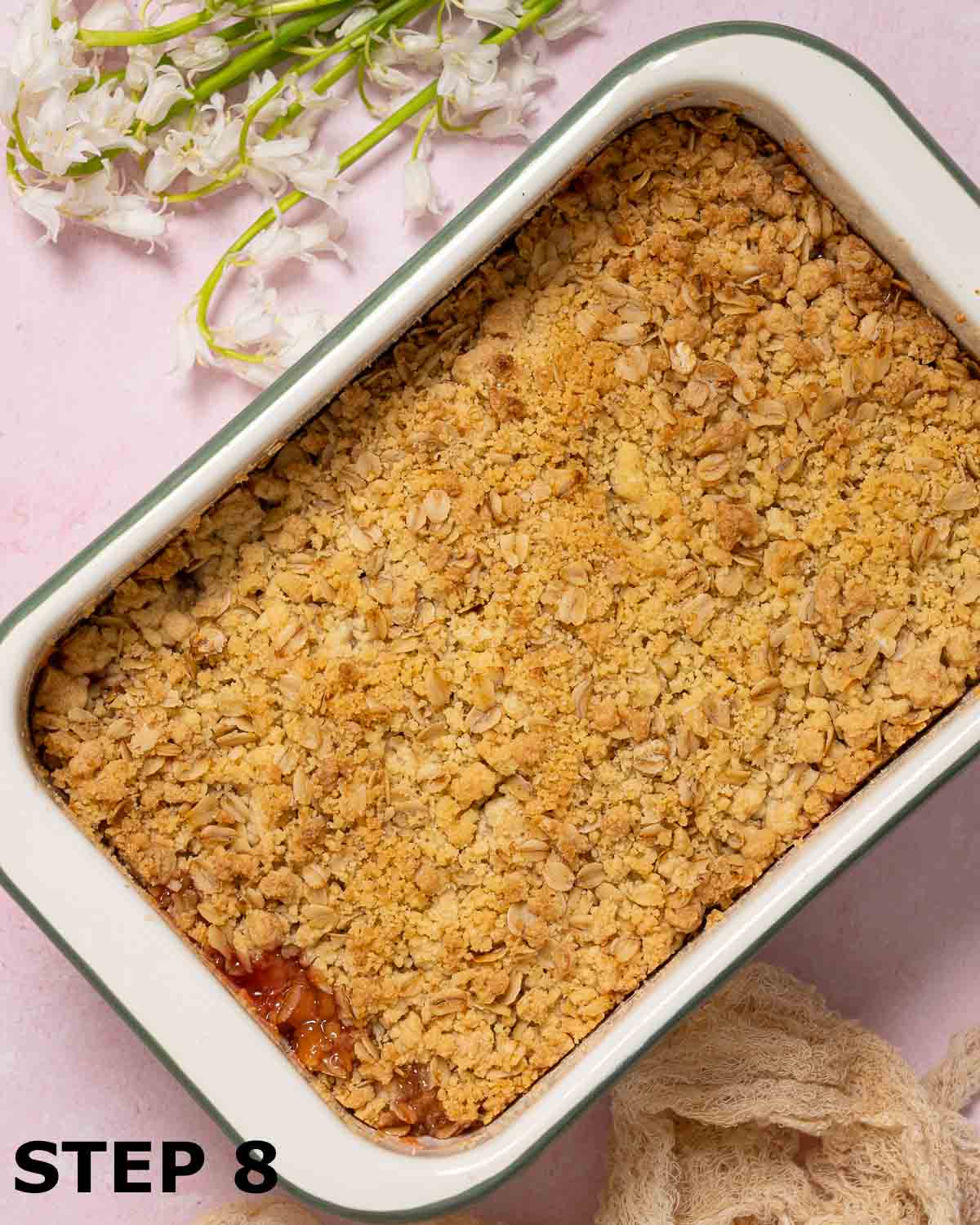 Freshly baked fruit crumble on a pink background.