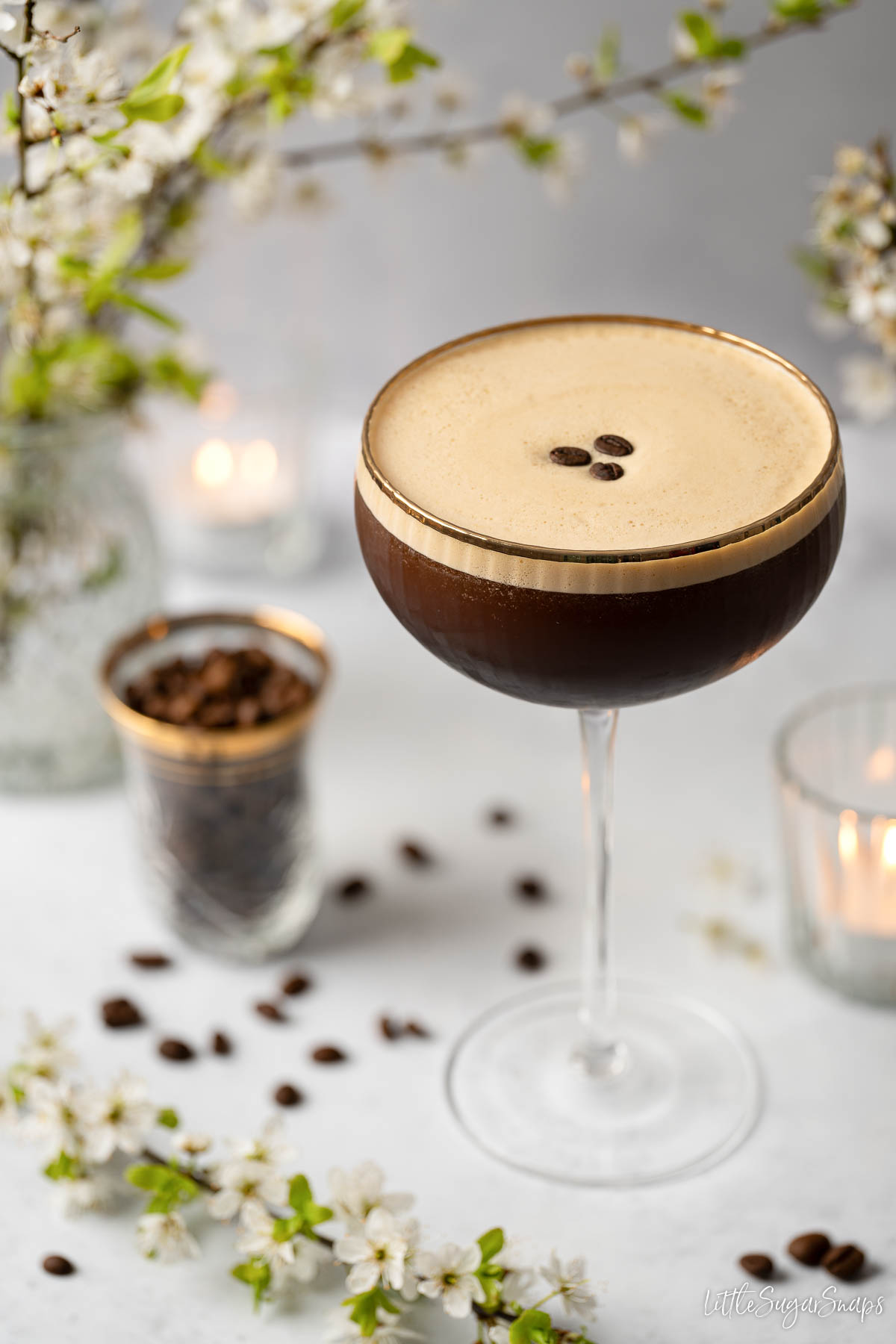 A caffe shakerato in a cocktail glass with a gold rim and garnished with coffee beans.
