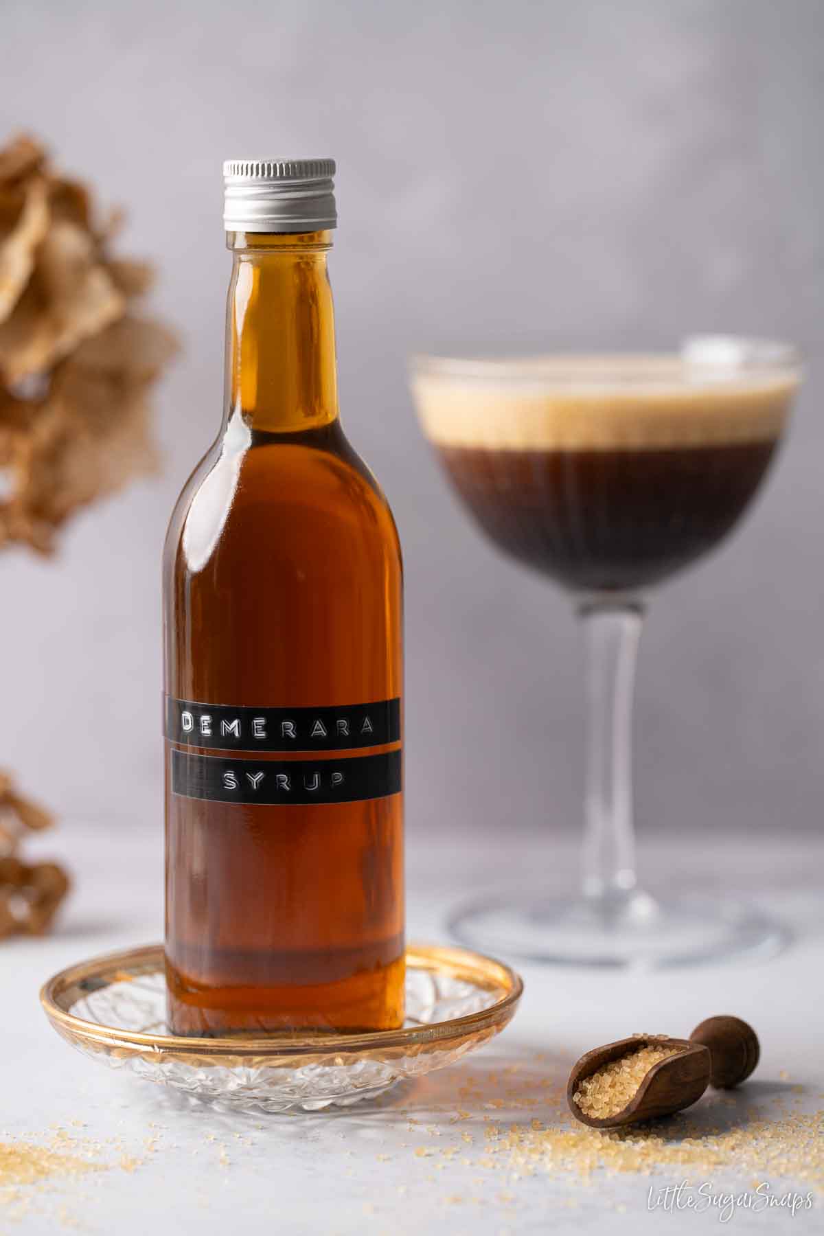 A labelled bottle of Demerara sugar syrup with a coffee cocktail in the background.