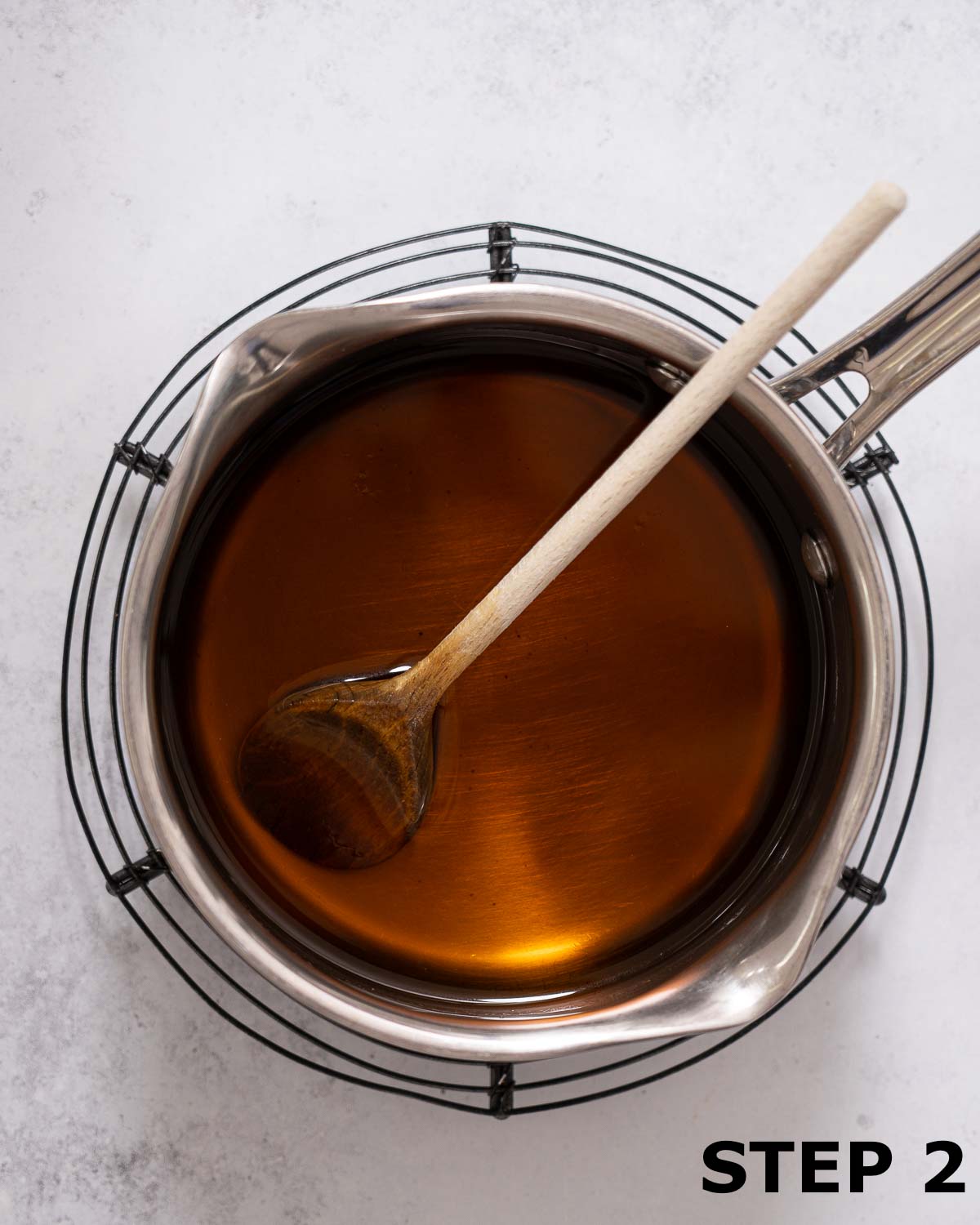Demerara simple syrup in a saucepan with a wooden spoon.