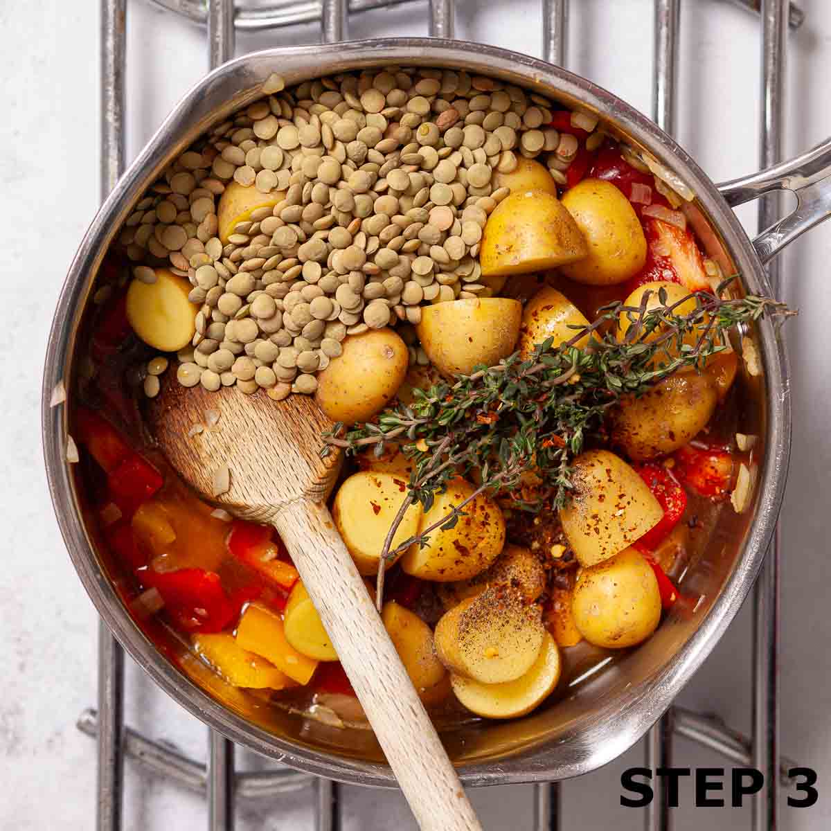Saucepan containing peppers, potatoes, dried green lentils and thyme.