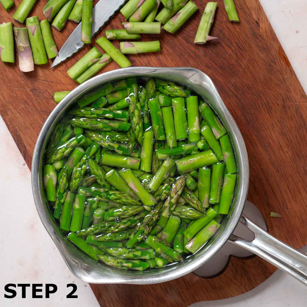 Chopped asparagus in a pan of hot water.