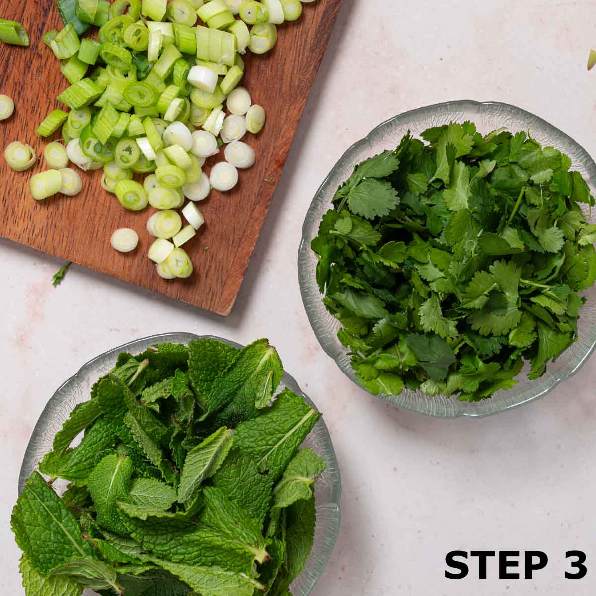 Sliced spring onions and bowls of mint and coriander.
