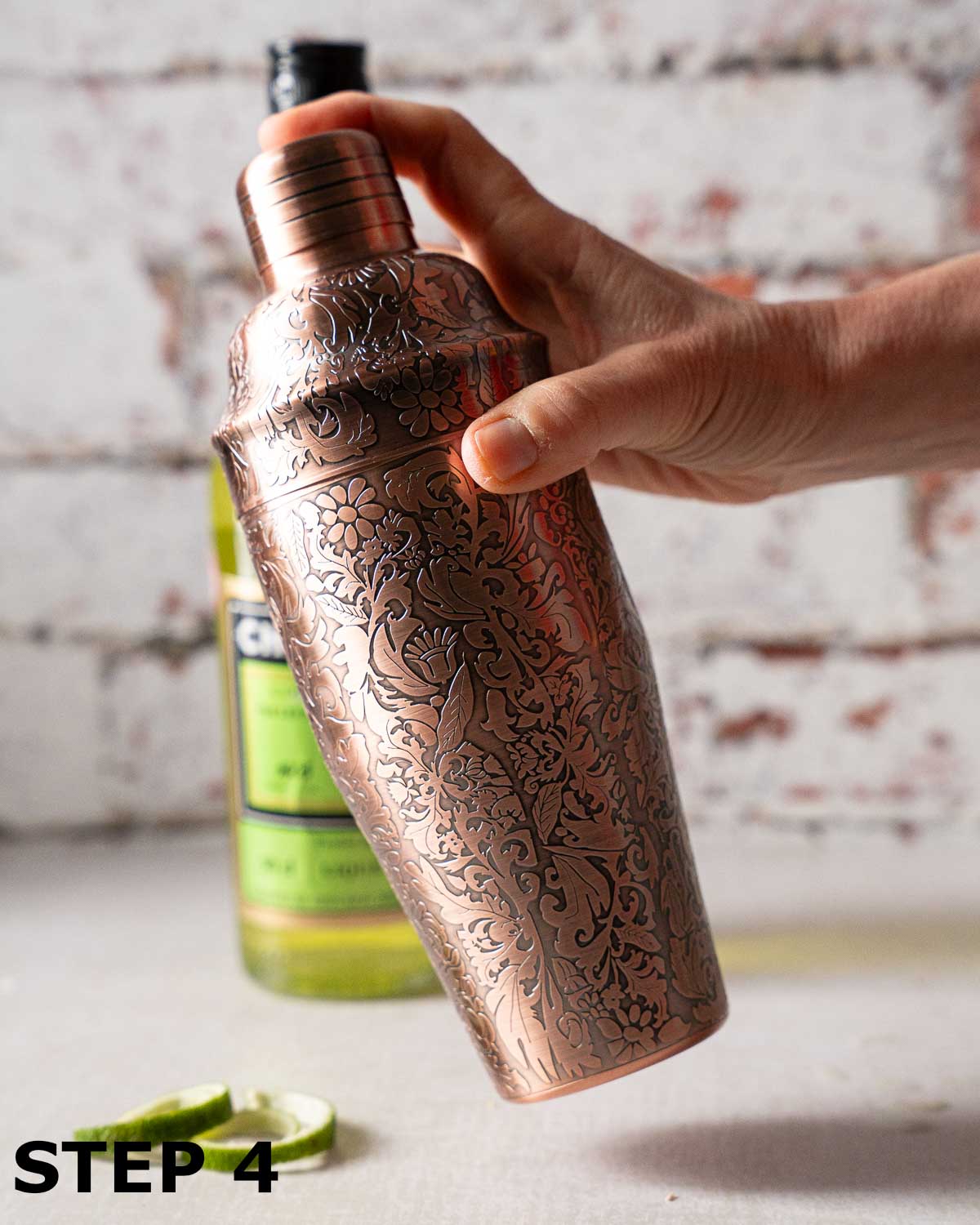 A person shaking a cocktail in a cocktail shaker.