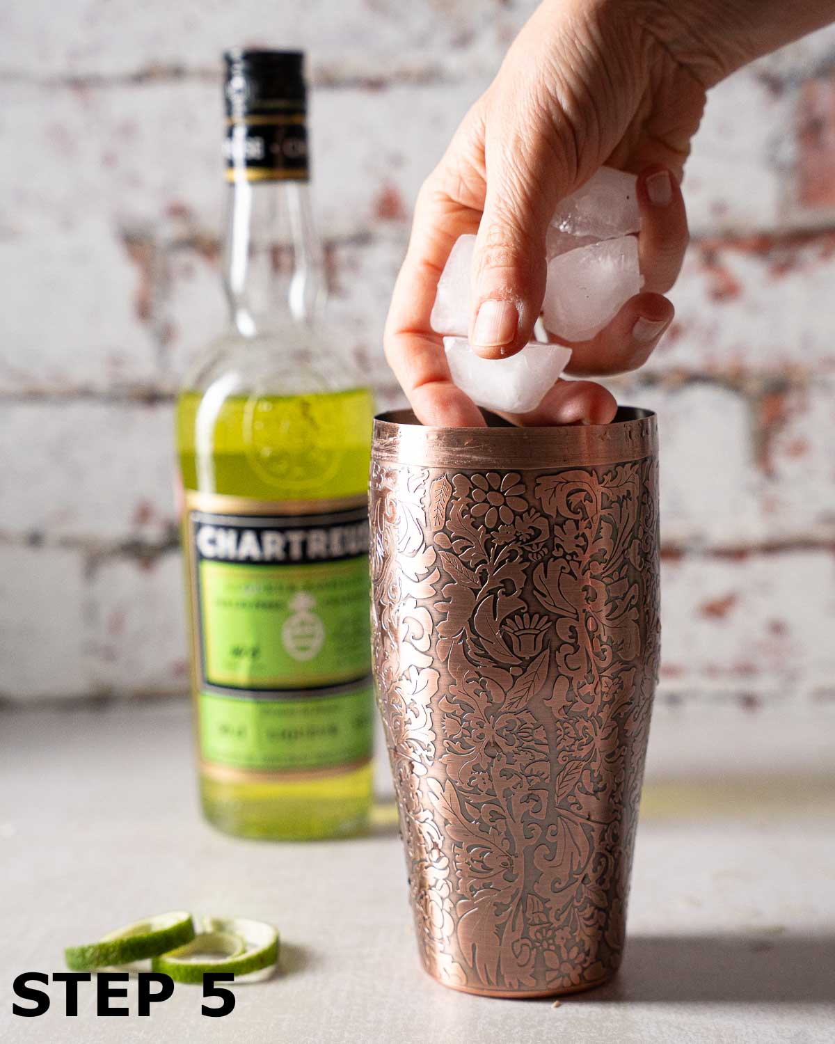 A person adding ice to a cocktail shaker.