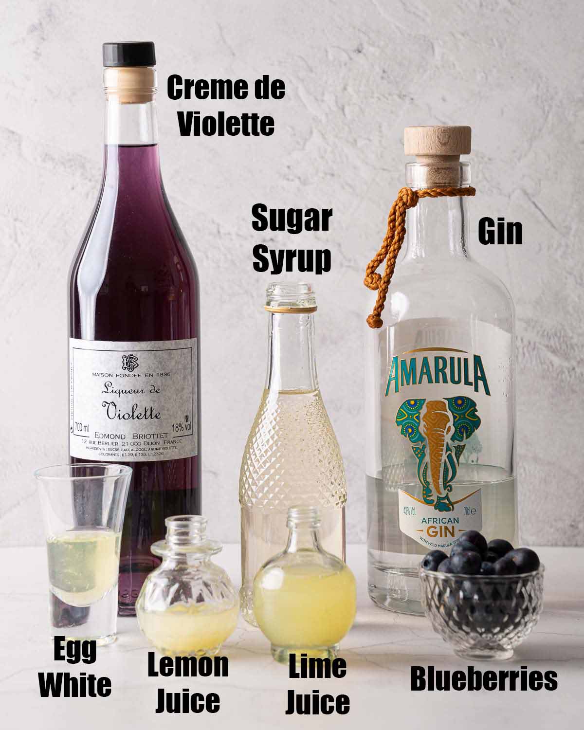 labelled ingredients for a blueberry gin cocktail with crème de violette.