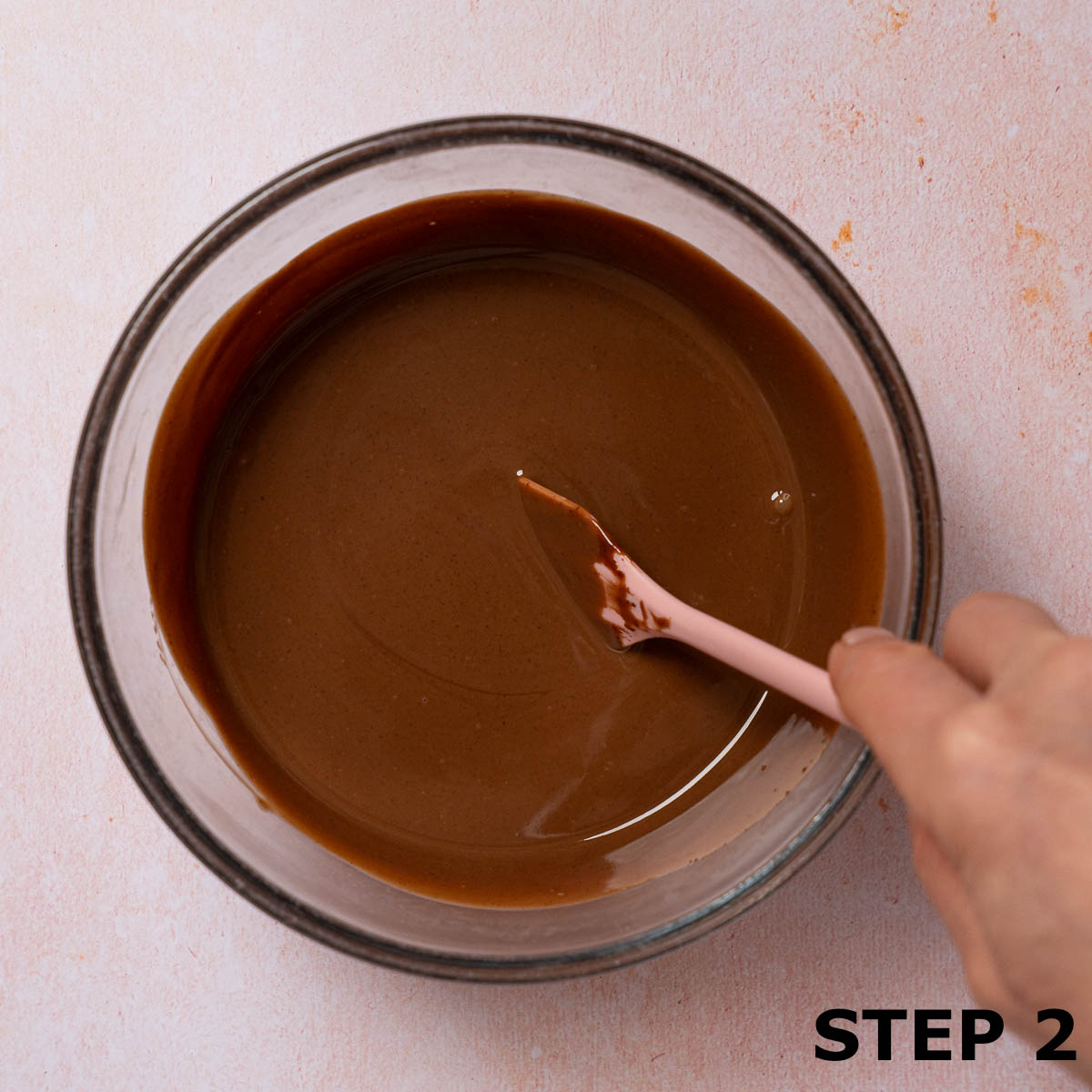 A person stirring chocolate dip in a bowl.