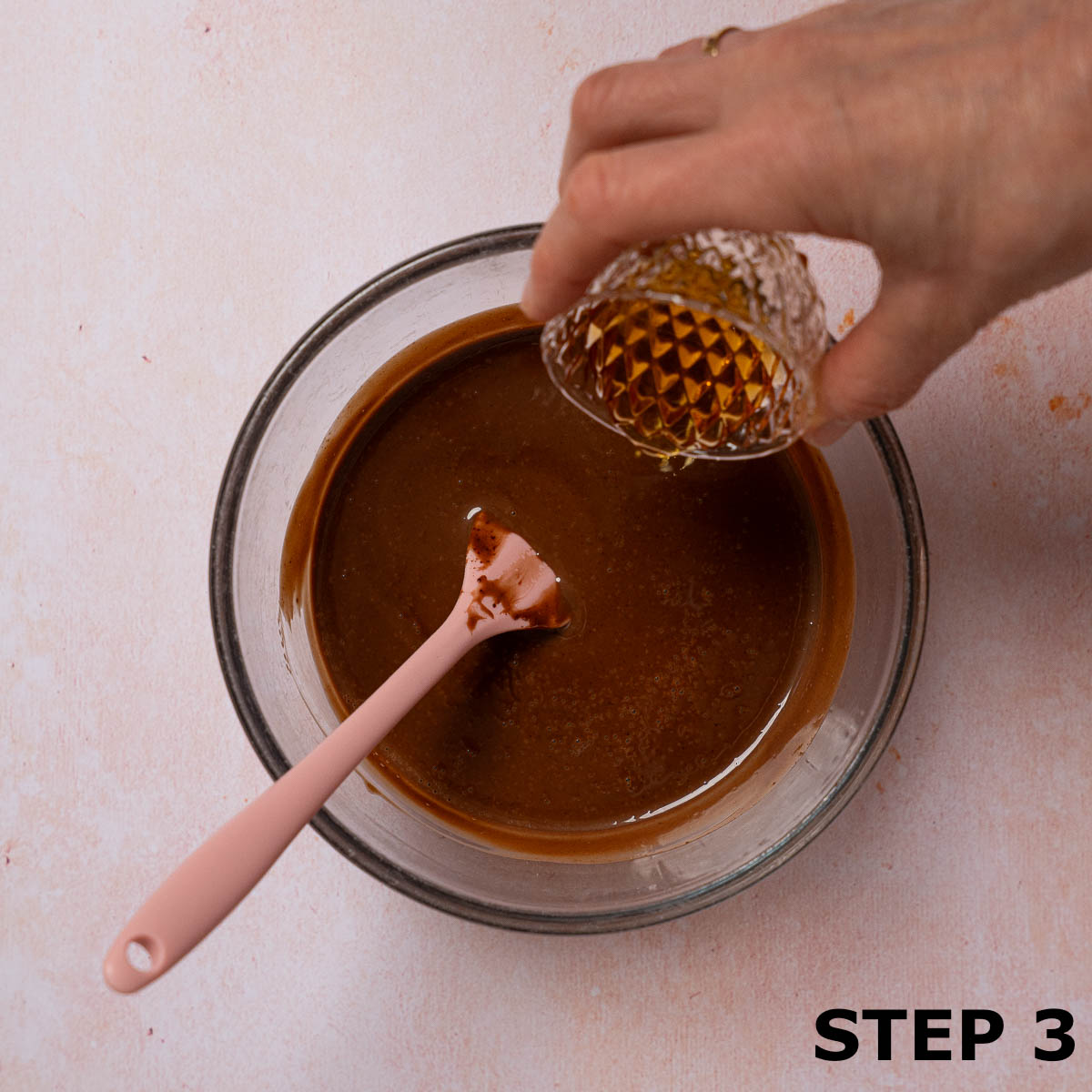 A person pouring maple syrup into a bowl of warm chocolate dip.