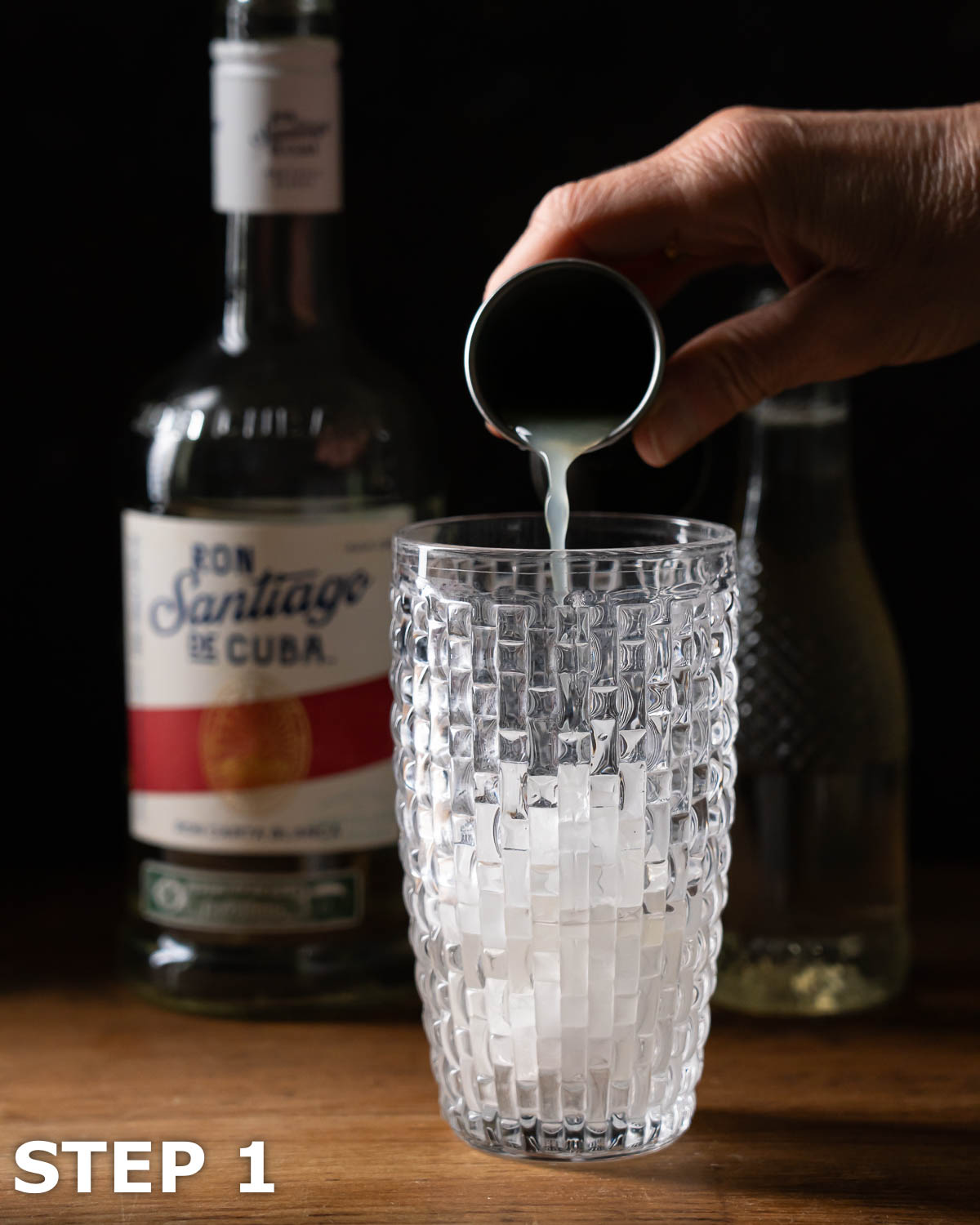 A person pouring lime juice into a cocktail shaker.